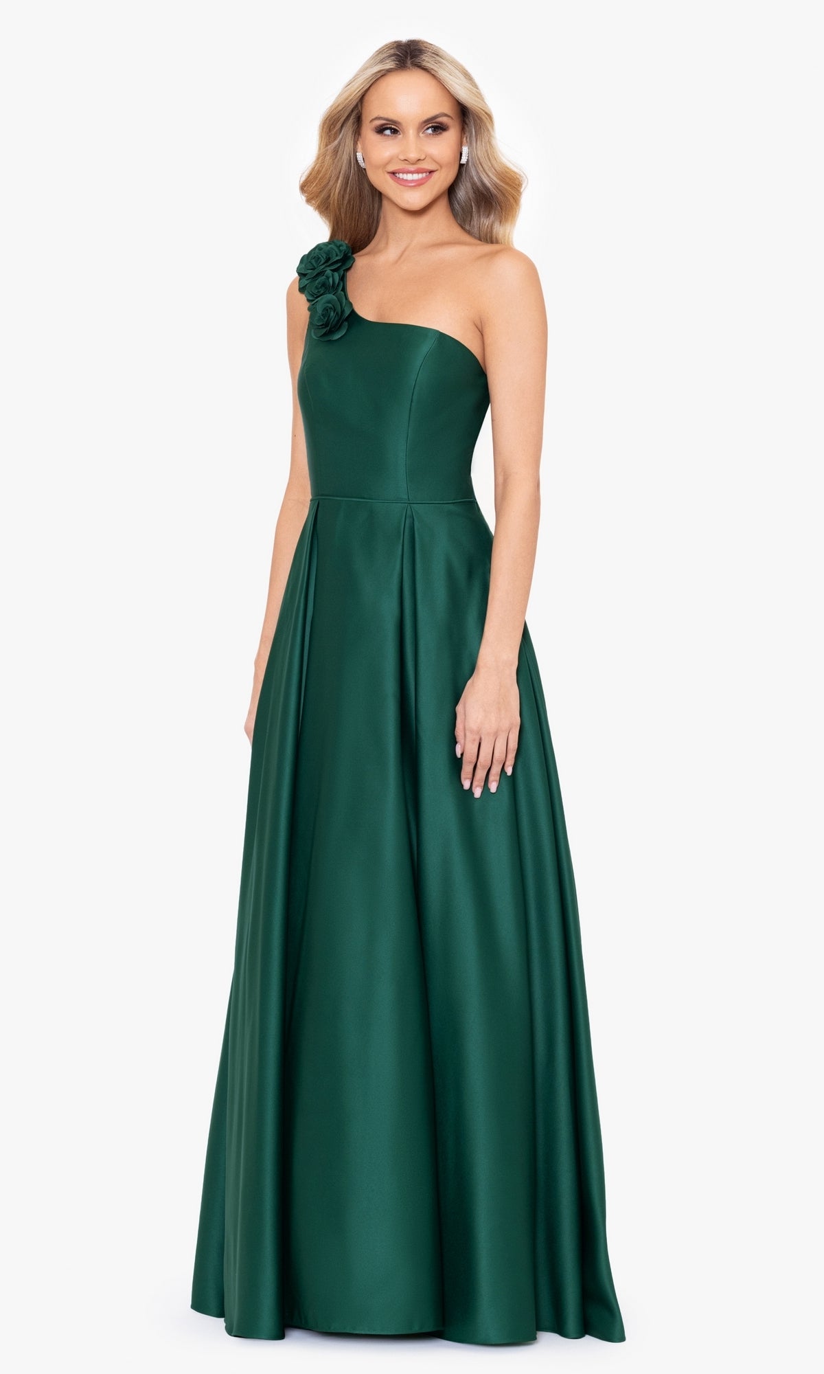 A woman stands against a plain white background wearing the Hunter Green One-Shoulder Long Prom Dress 4600BN, an elegant floor-length gown with a floral strap detail.